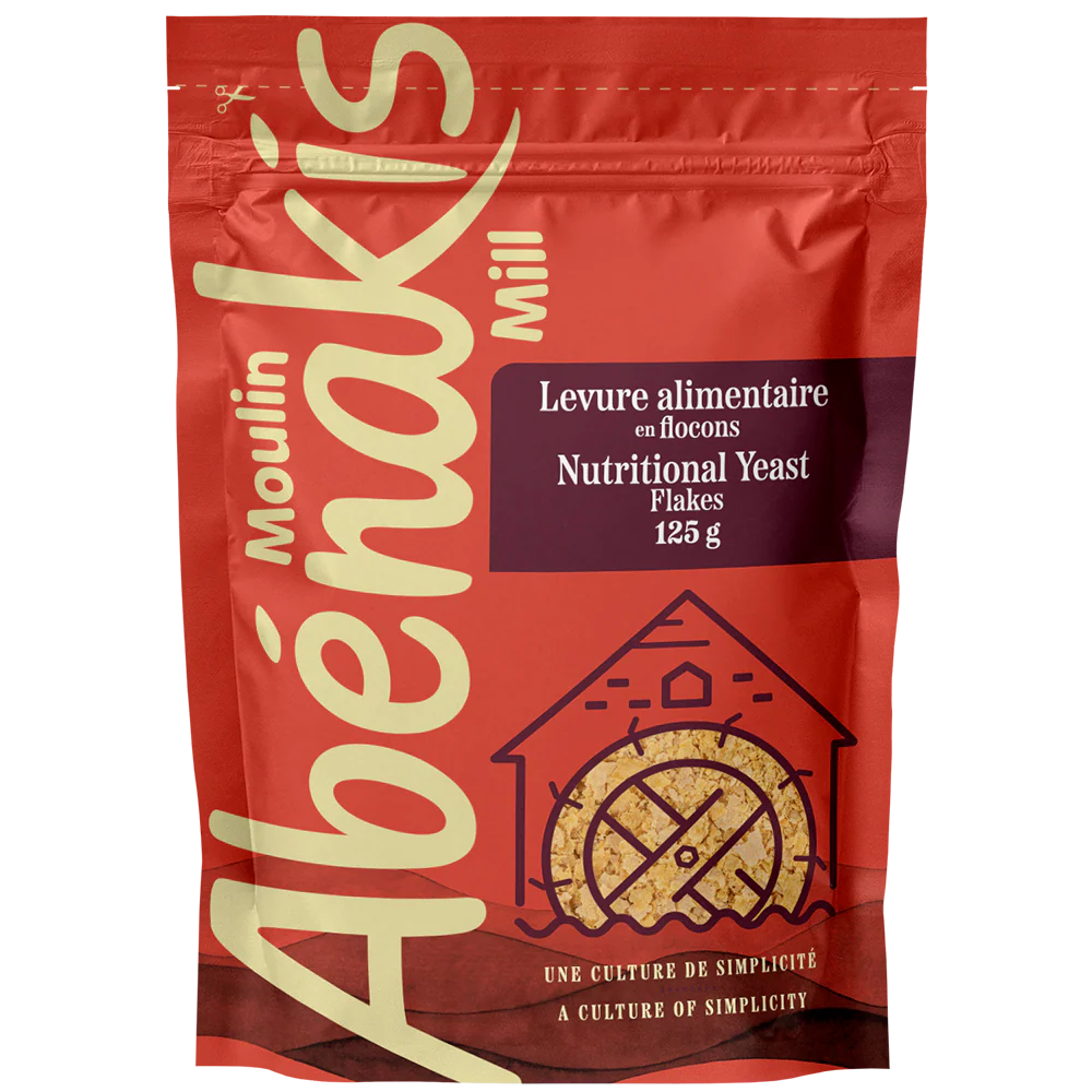 A bag of ABÉNAKIS grilled nutritional yeast flakes, featuring golden flakes used as a savory, cheesy-flavored seasoning.