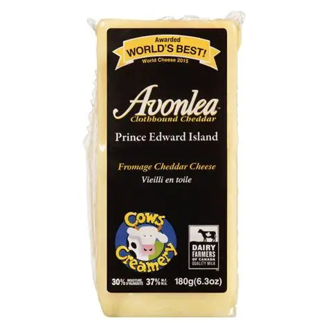A block of Cows Creamery Avonlea raw milk cheddar cheese, featuring a firm texture and rich orange color in branded packaging.
