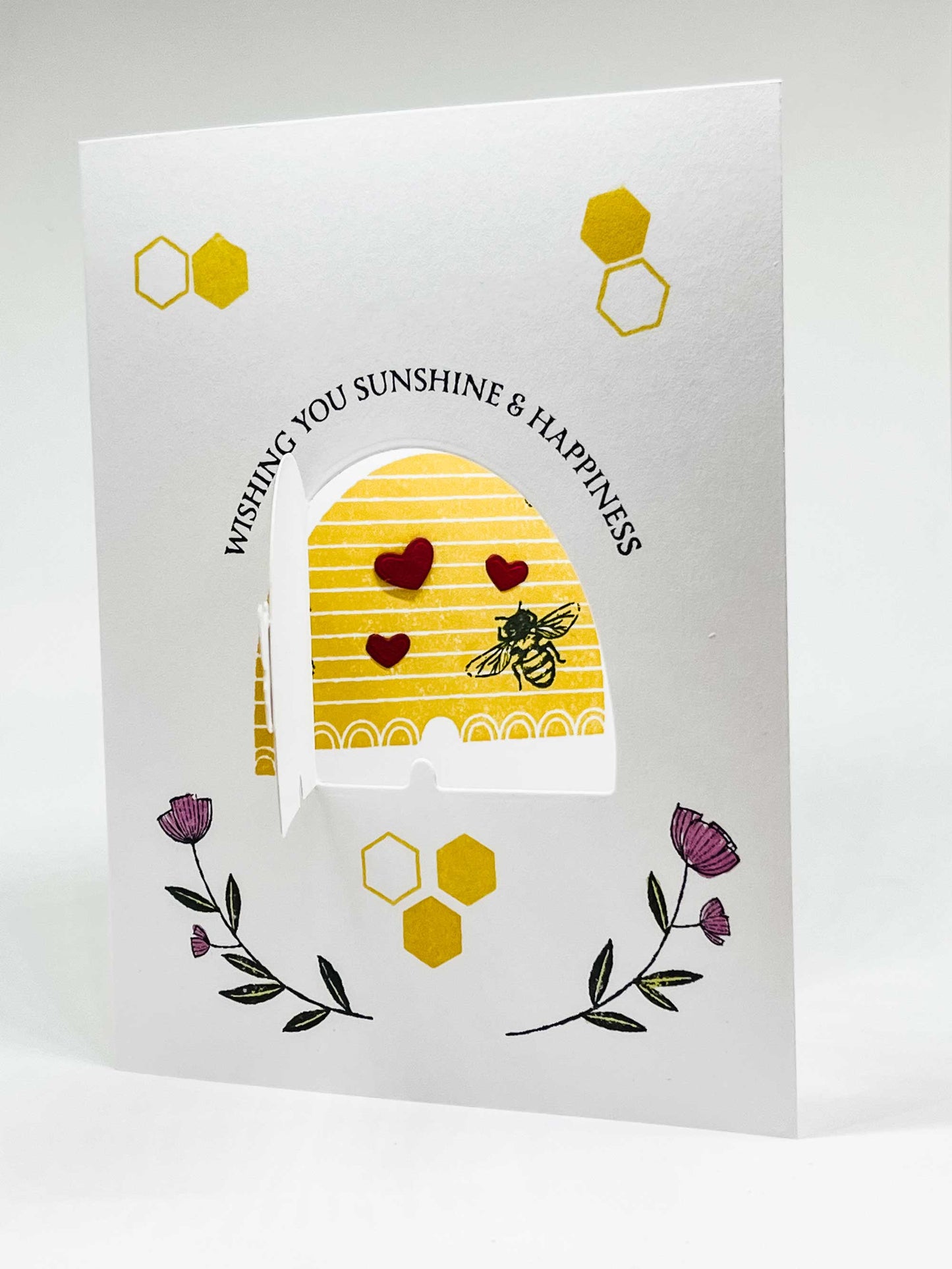 Pop-up greeting card with honeybee on a hive surrounded by hearts and flowers and text that wishing you sunshine & happiness