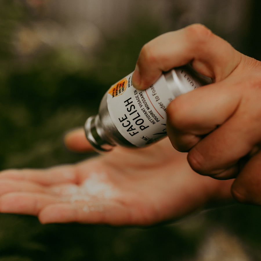 Hand shaking out Bee by the Sea cleansing powder from aluminum bottle into other hand