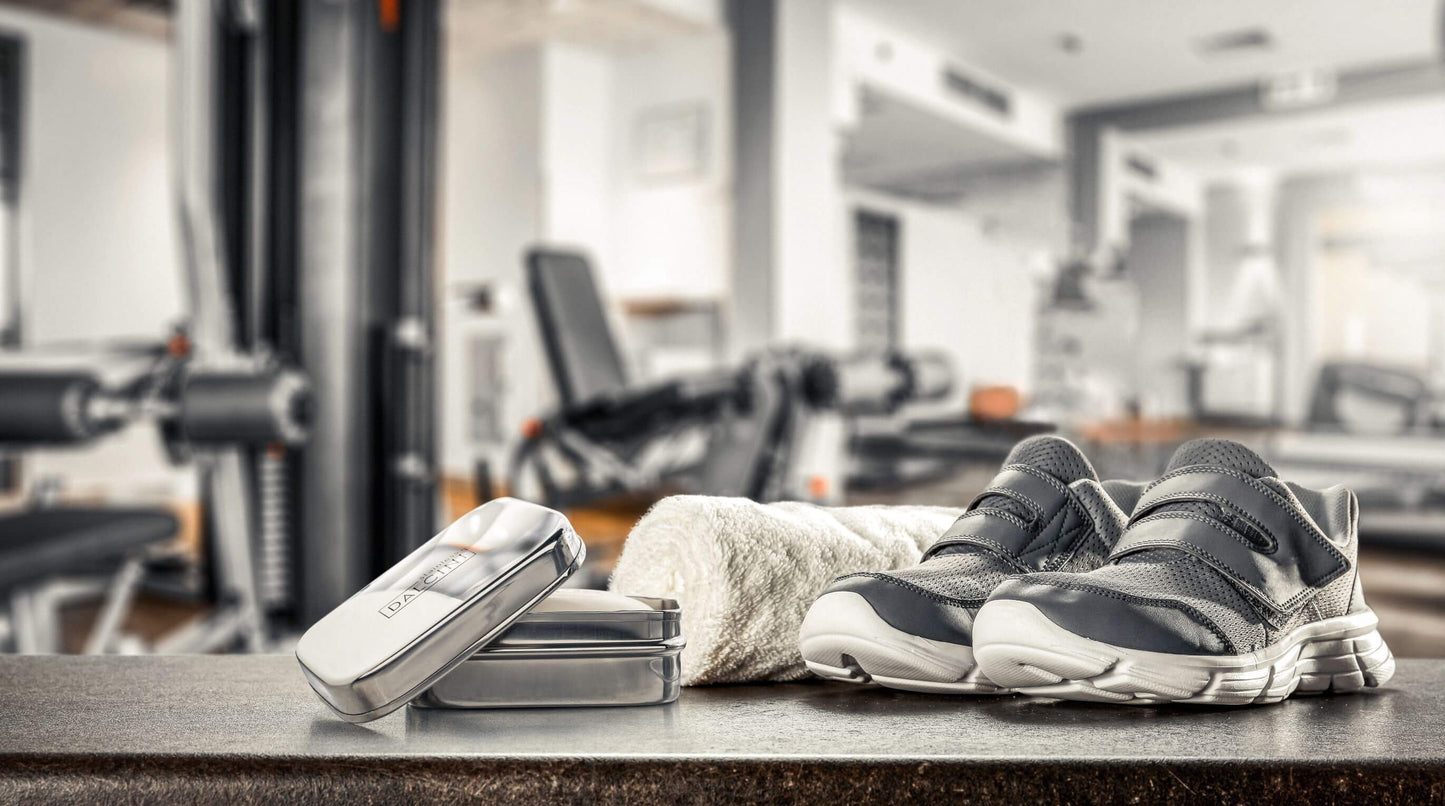 Food-grade stainless steel soap dish open on gym counter next to pair of sneakers and rolled up towel