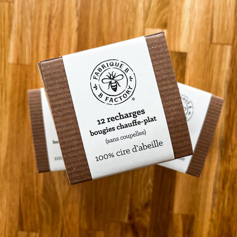 Stacked cardboard gift boxes with packaging that says B Factory 12 tea lights refills without cups, 100% beeswax