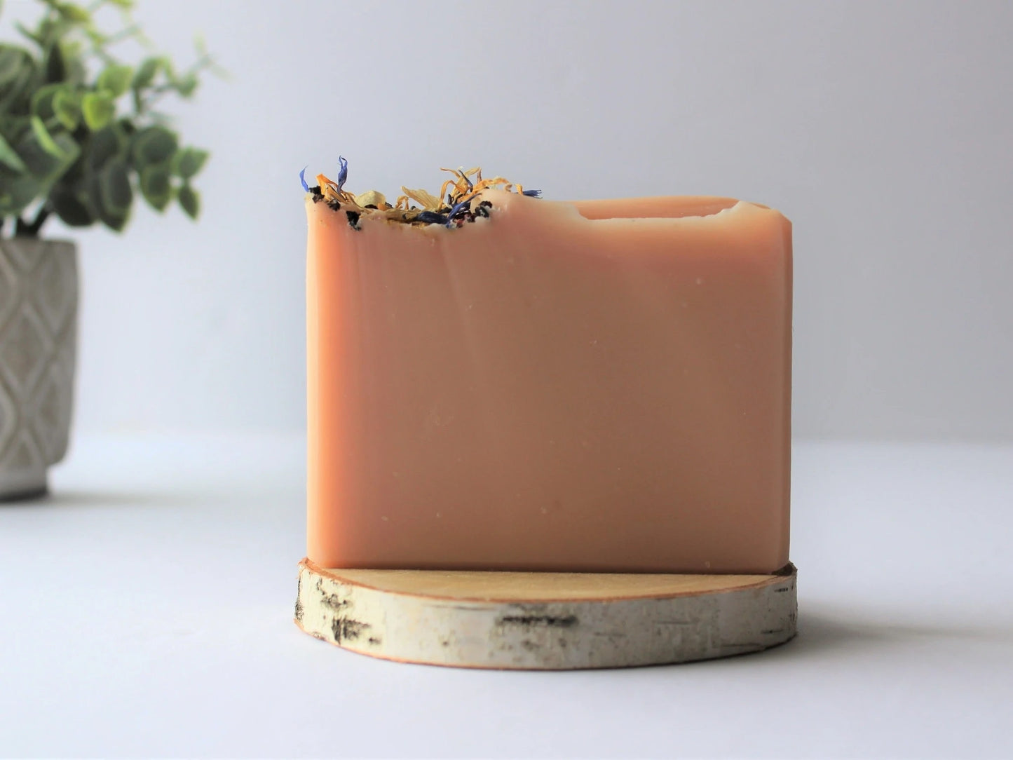 Handmade natural floral soap bar on wood platform