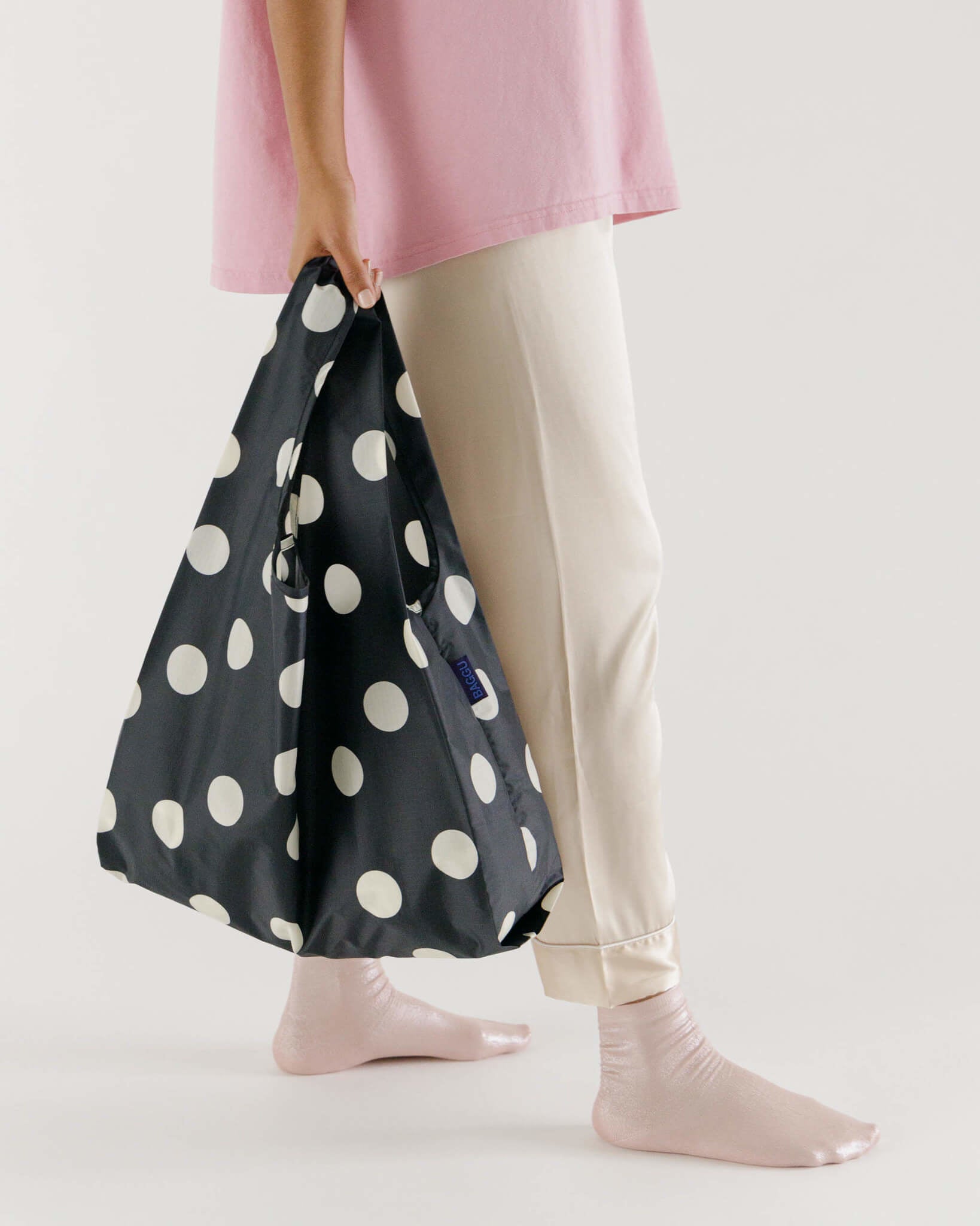 Person walking with full reusable shopping bag with white polka-dot pattern