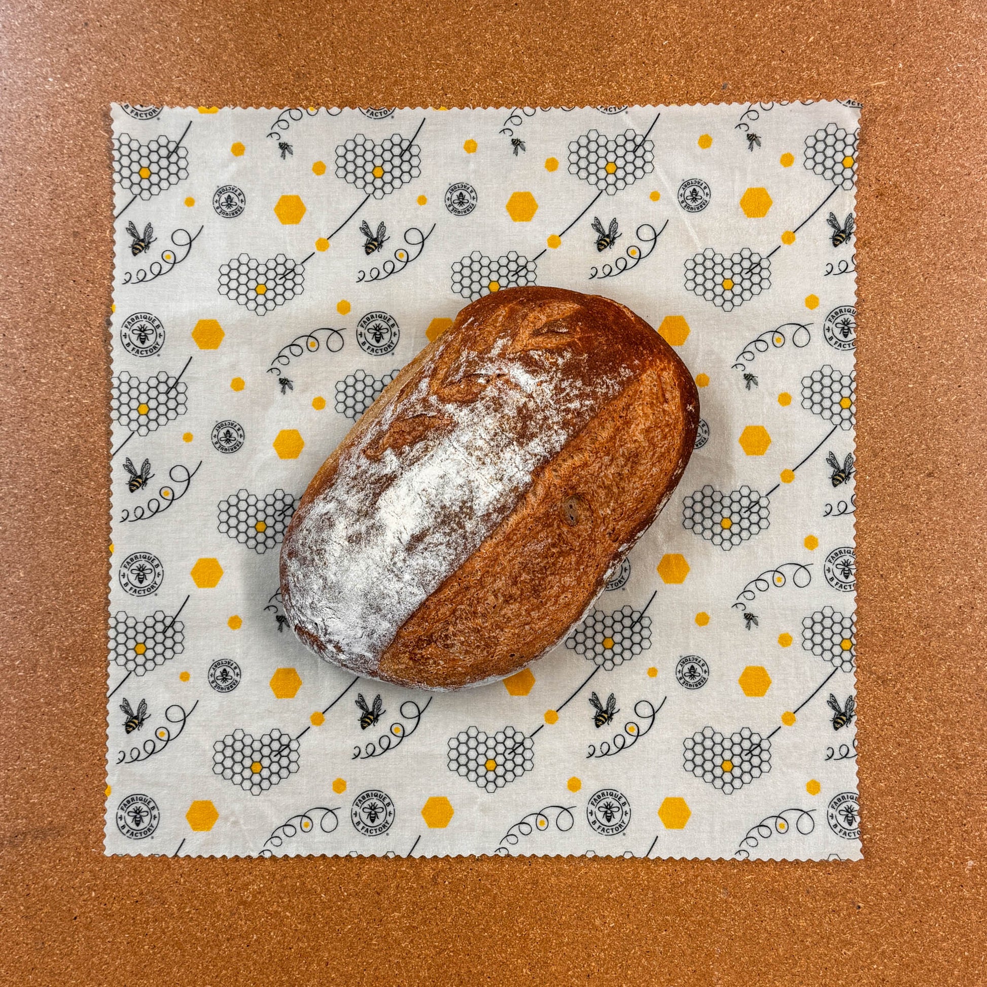Loaf of bread on a patterned beeswax wrap against a brown background