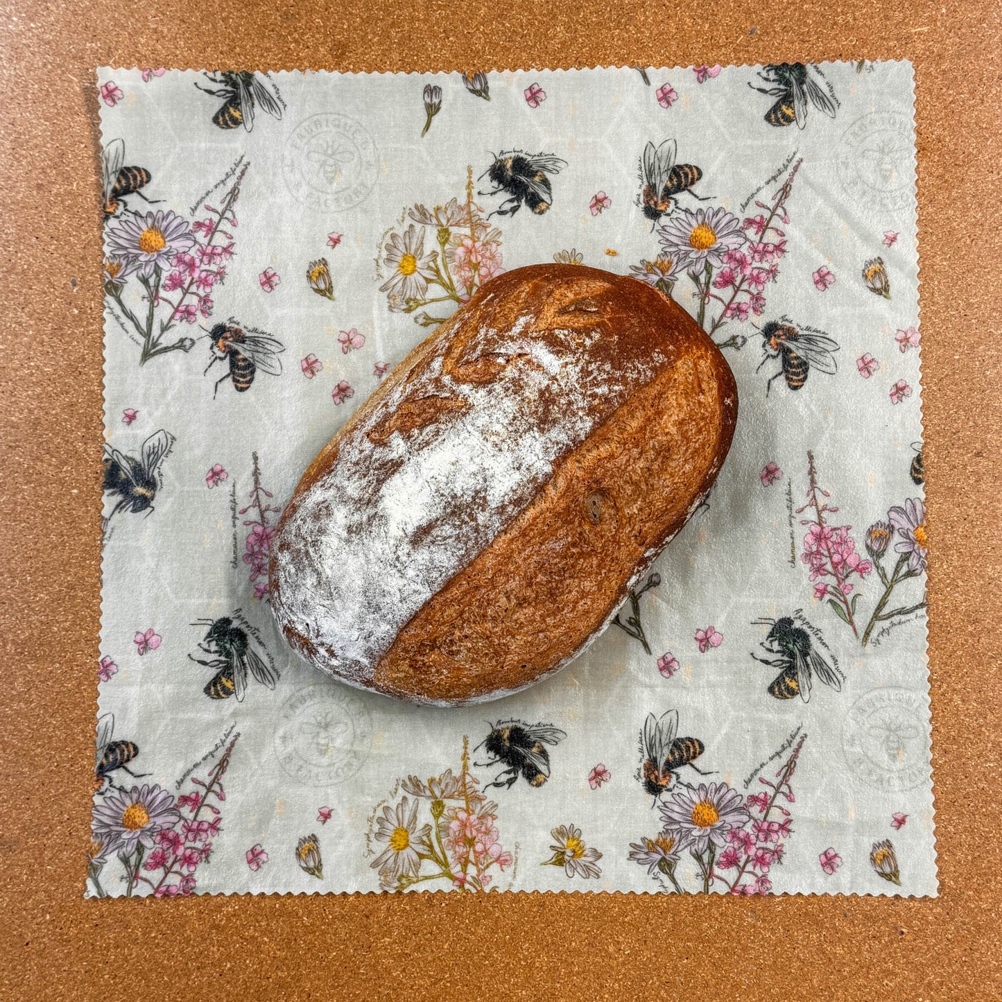 Loaf of bread on a floral-patterned beeswax wrap with a brown background