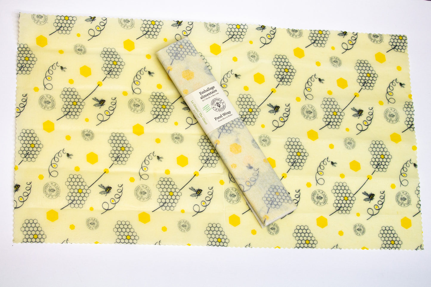 One giant rectangular beeswax foodwrap with honeycomb and B Factory logo pattern, with a wrapped version sitting in the middle