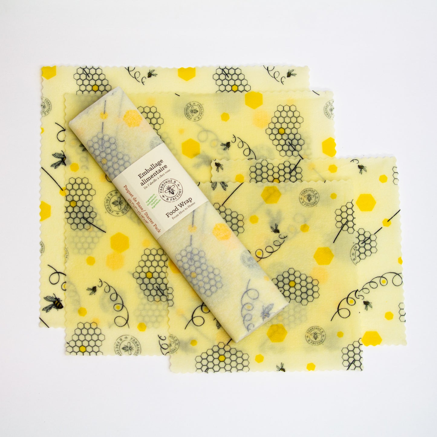 Starter pack of beeswax food wraps set upon 2 medium and 2 small food wraps with bee and honeycomb pattern with B Factory logo