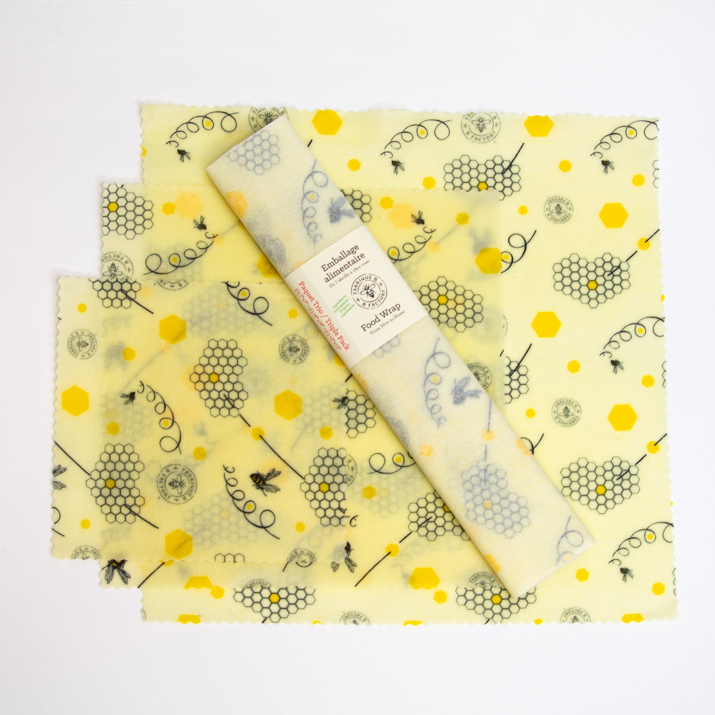 Trio pack of beeswax food wraps set  upon one small, one medium, one large beeswax food wrap with honeycomb and bee pattern with B Factory logo