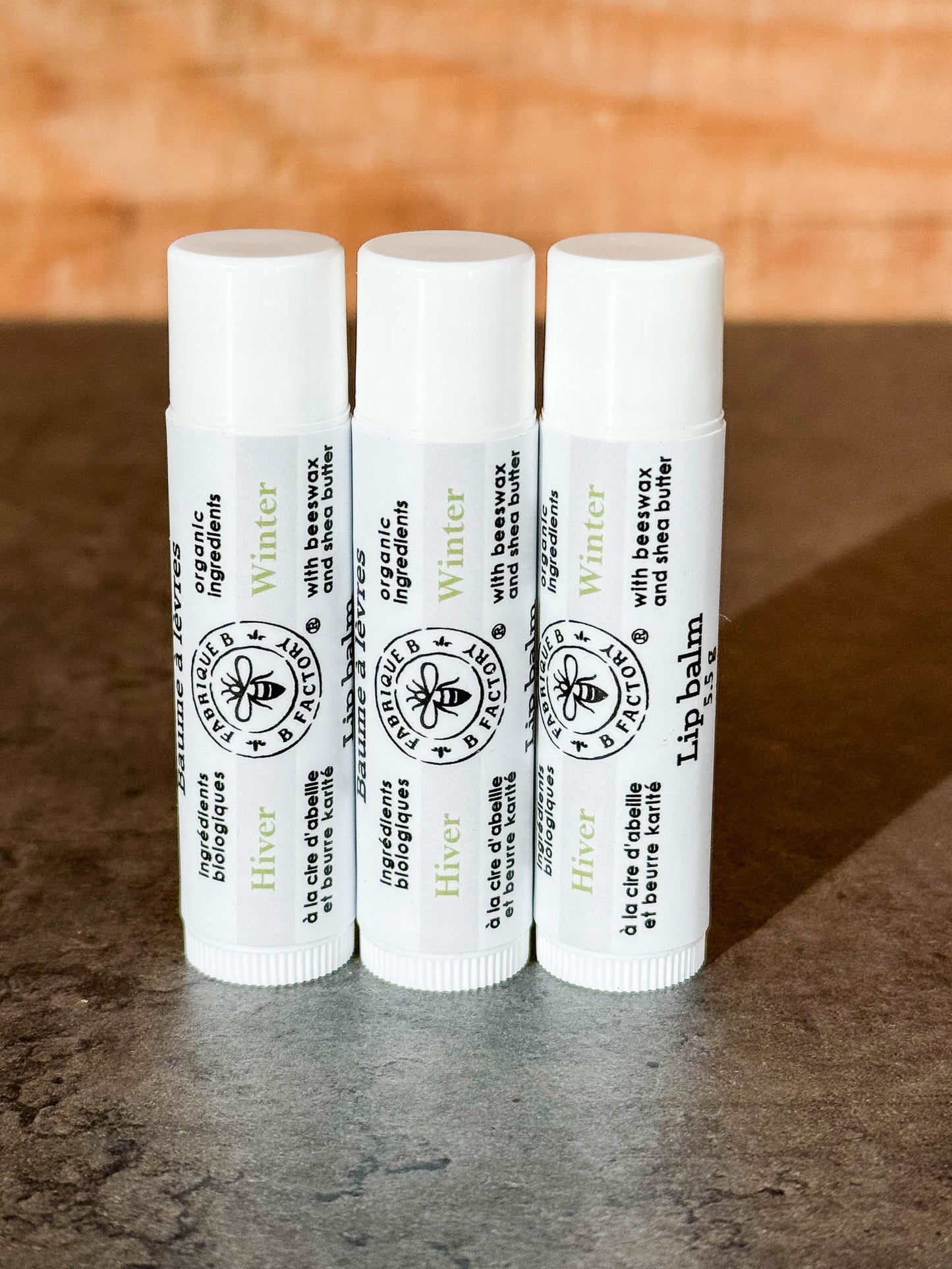 B Factory winter lip balm with spearmint on counter with wood background