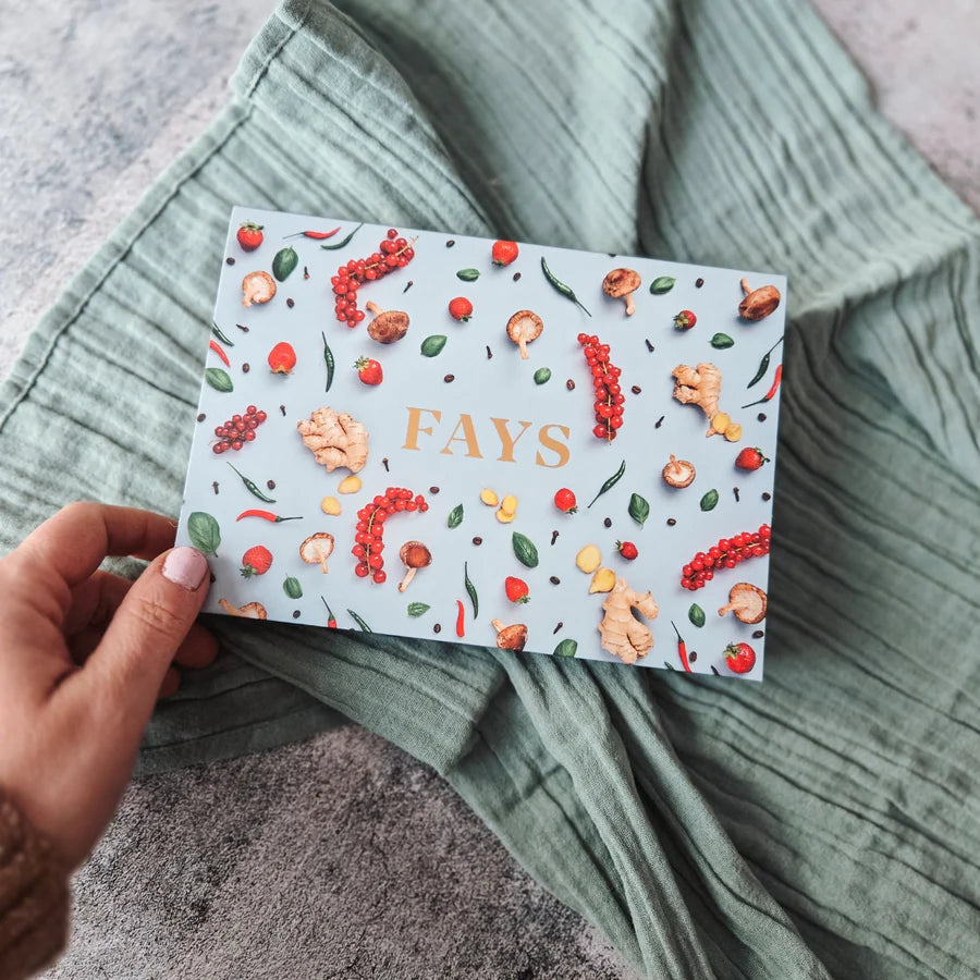 Box with decorative elements and 'FAYS' branding held by a hand on a textured surface.