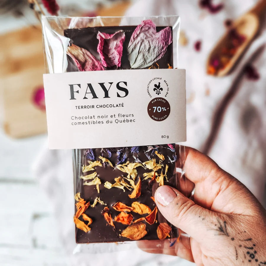 Hand holding a package of FAYS dark chocolate with edible dried flowers on a light background
