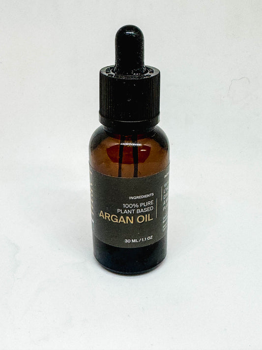 An amber bottle of pure Argan oil with a dropper top on a white background