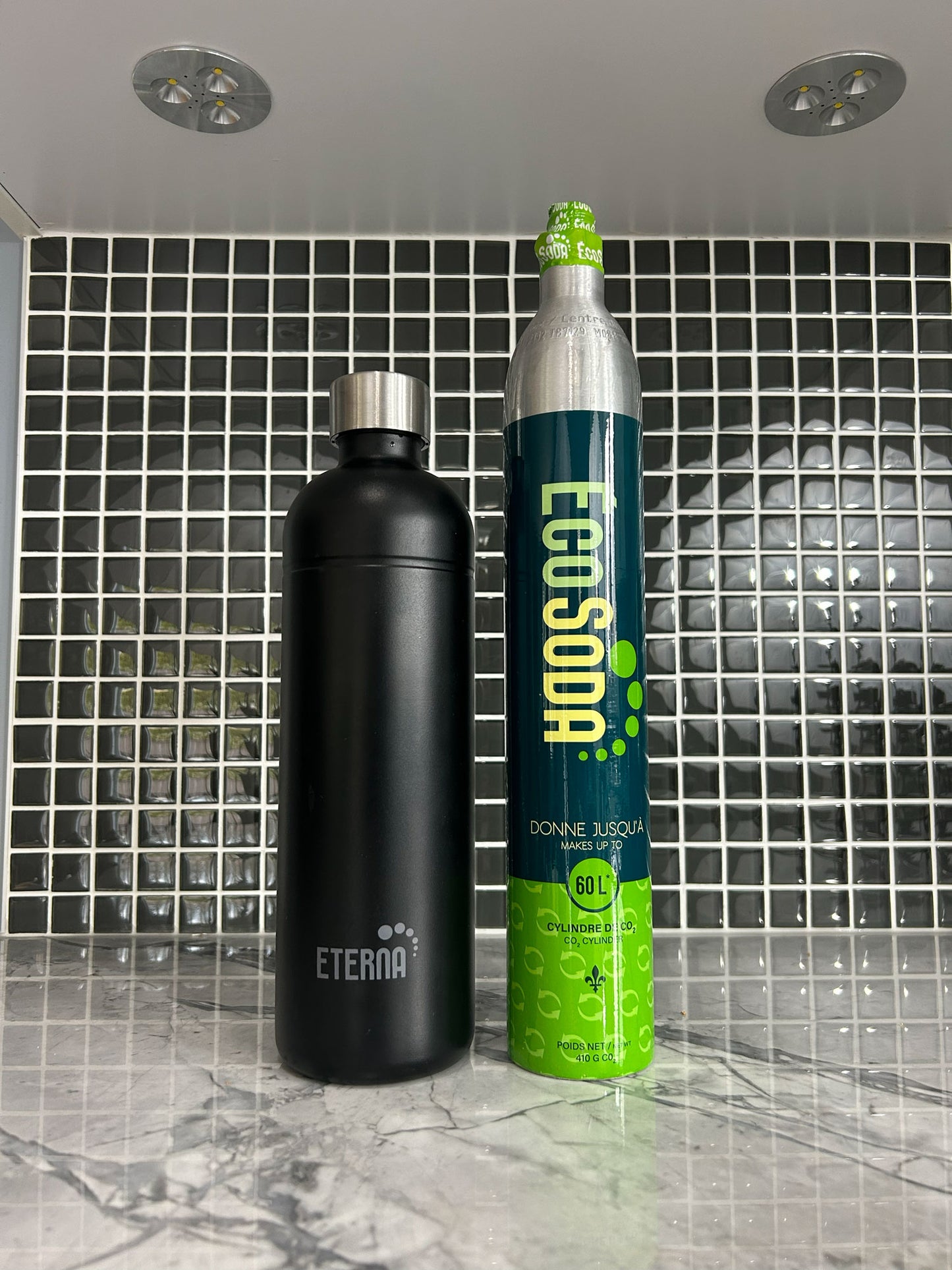 Black Eterna water bottle and Ecosoda canister on a tiled counter