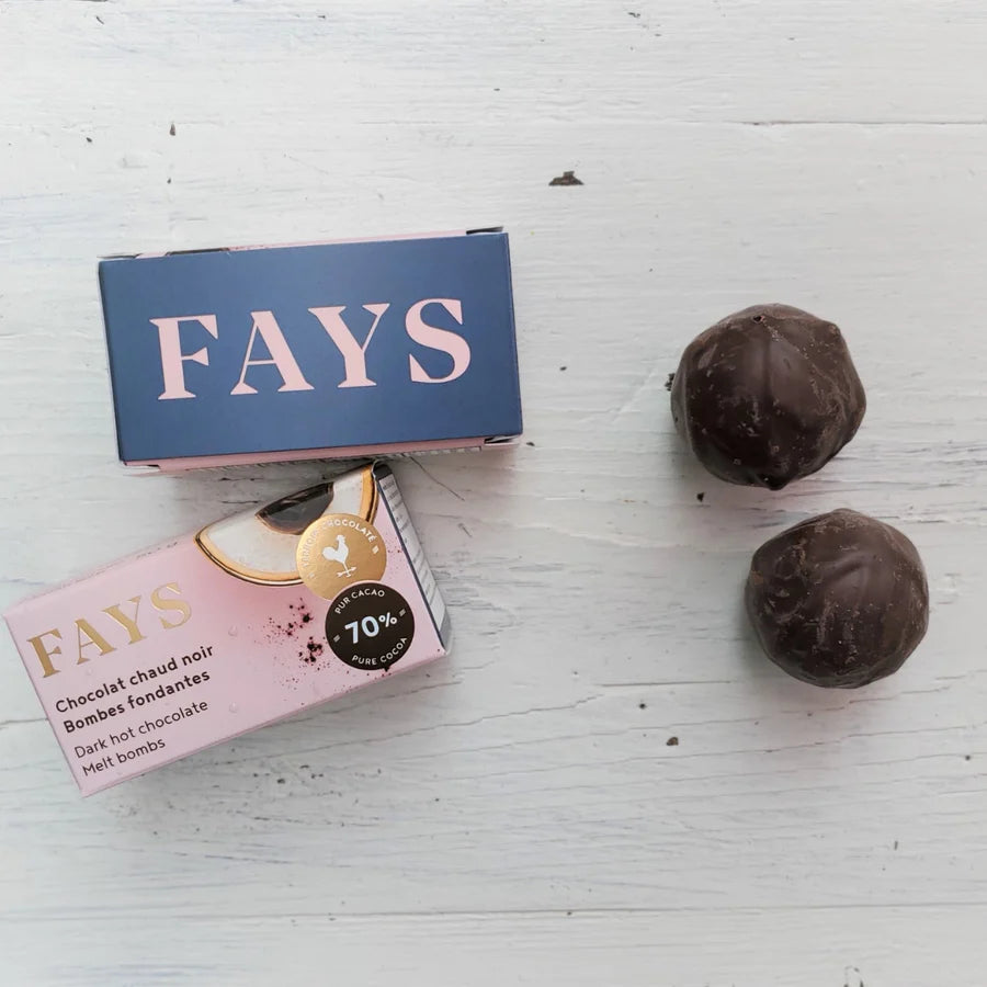 Two boxes of FAYS dark hot chocolate bombs on a light wooden surface.