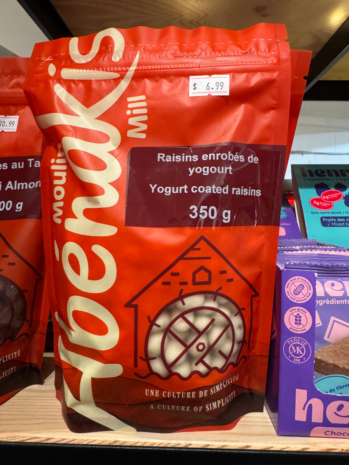 Abénakis Yogurt coated raisins in orange bag on a wood shelf
