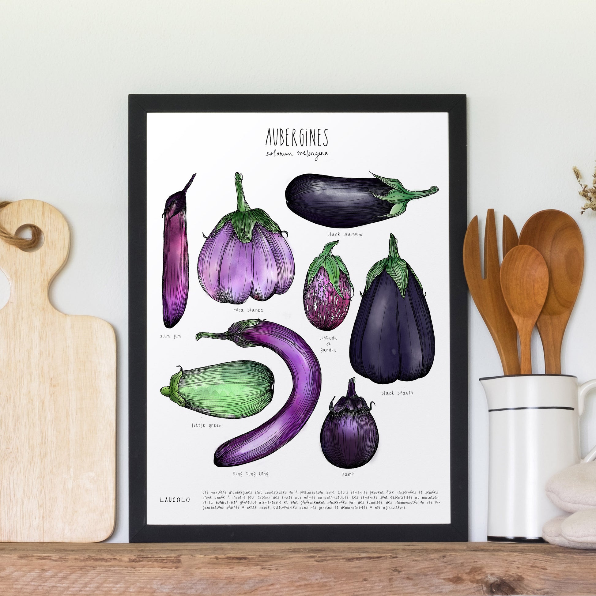 Eggplant illustration poster in black frame leaning against wall next to wood cutting board and jar with wood utensils