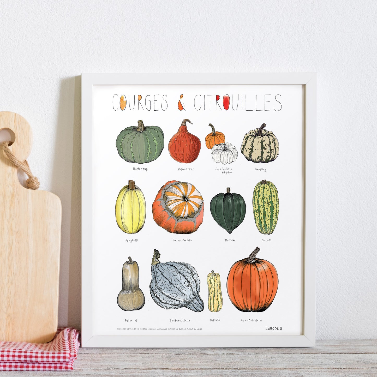 Pumpkins and gourds illustration poster in white frame leaning against wall next to wood cutting board