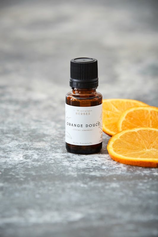 A brown glass bottle with Orange Douce essential oil and slices of orange on the side