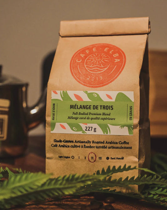 A bag of Café Elba whole bean coffee Mélange de Trois, featuring a balanced blend of roasted coffee beans in sealed, branded packaging.
