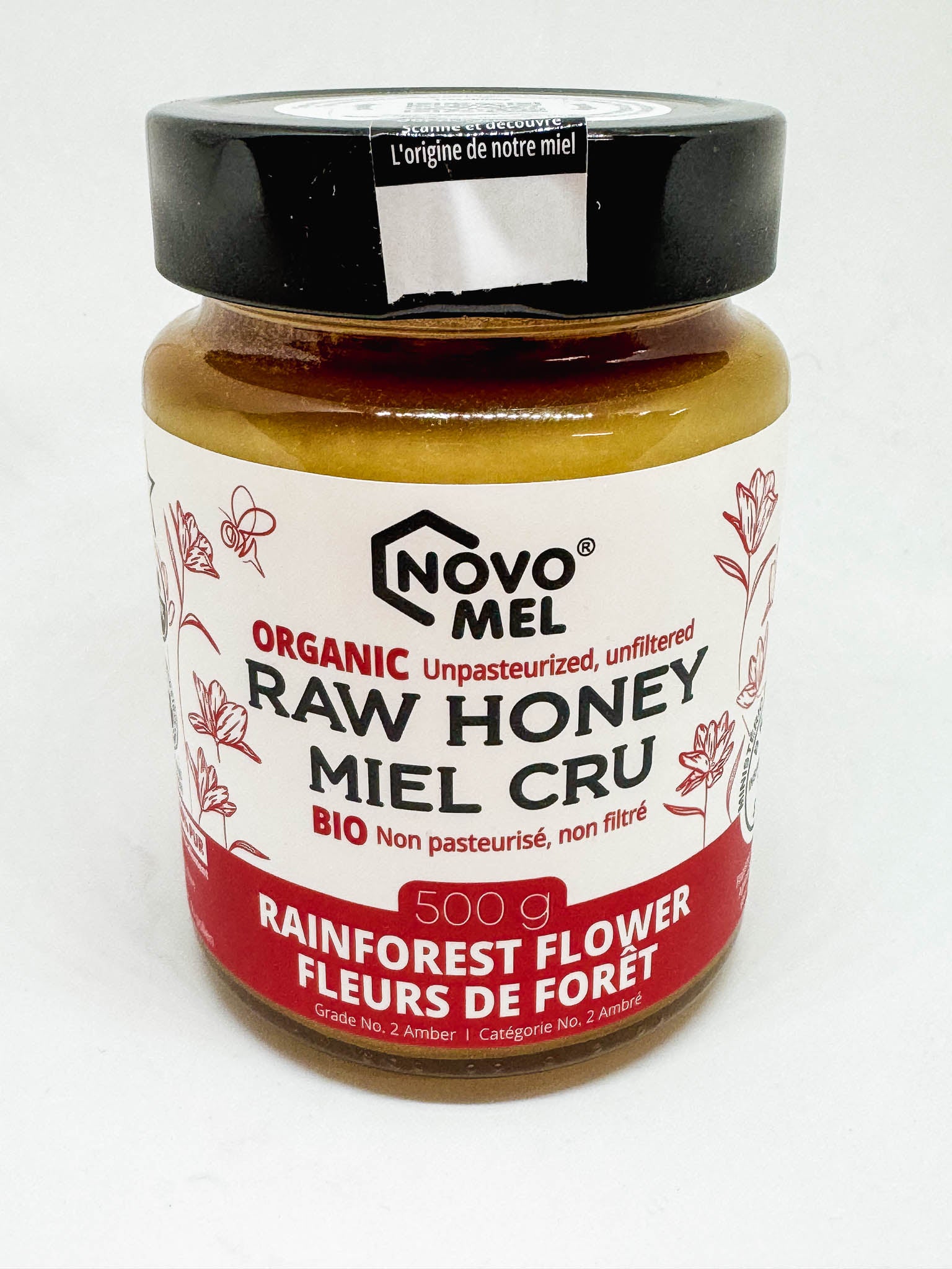 A jar of Novo Mel's organic raw rainforest flower honey on a white background