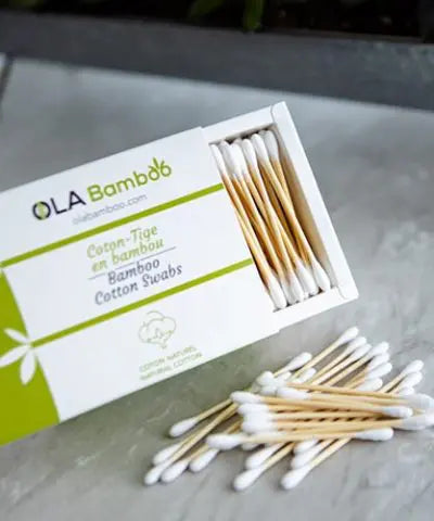 Close up of box of Ola Bamboo cotton swabs, with a pile of cotton swabs on table in front of box