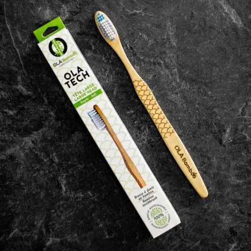 OLA Bamboo toothbrush with box "ola tech" to left, both set on a slate grey background