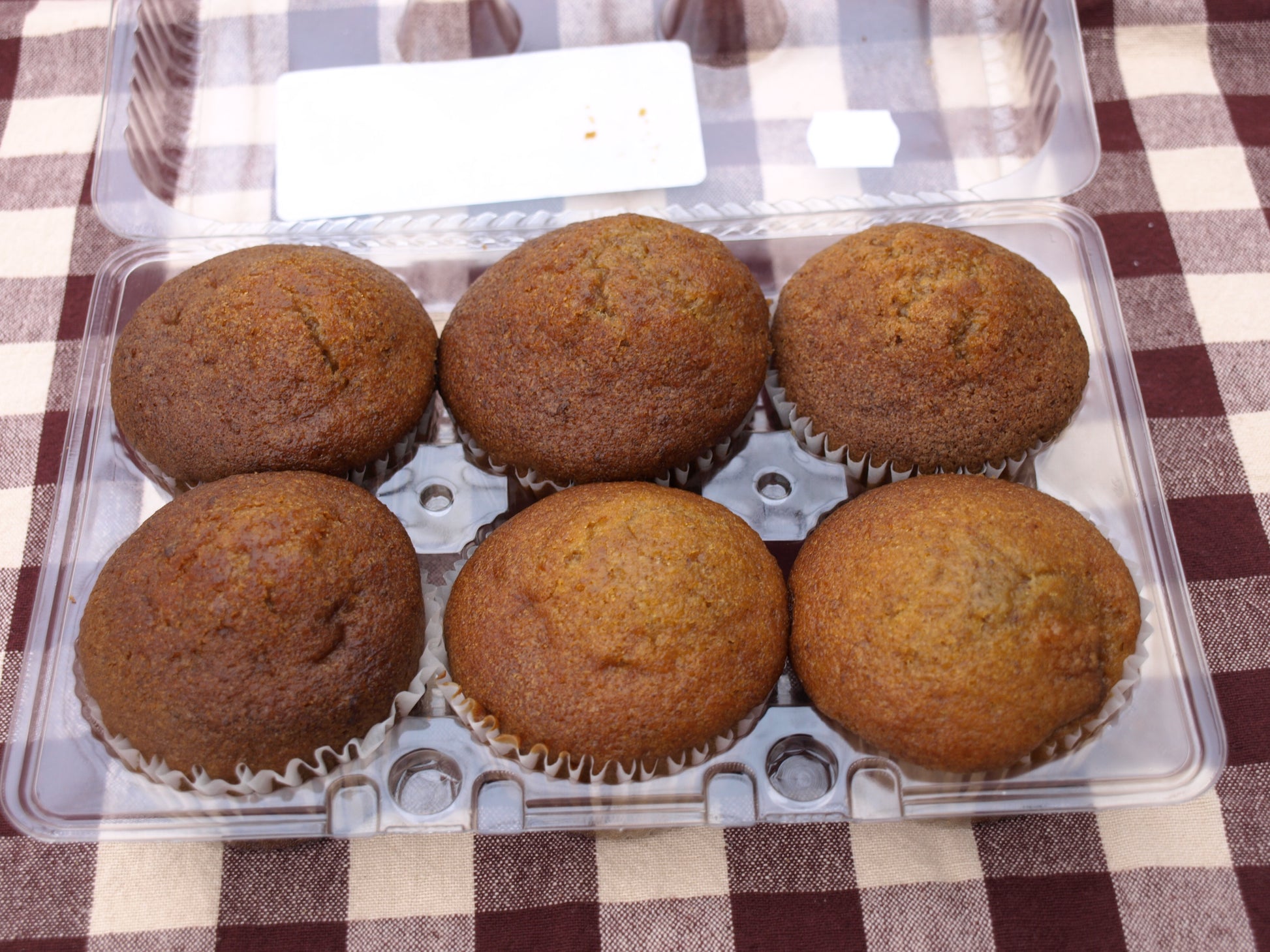 Six Quinn Farms pumpkin muffins, showcasing a soft, spiced muffin with a warm orange color in a plastic container