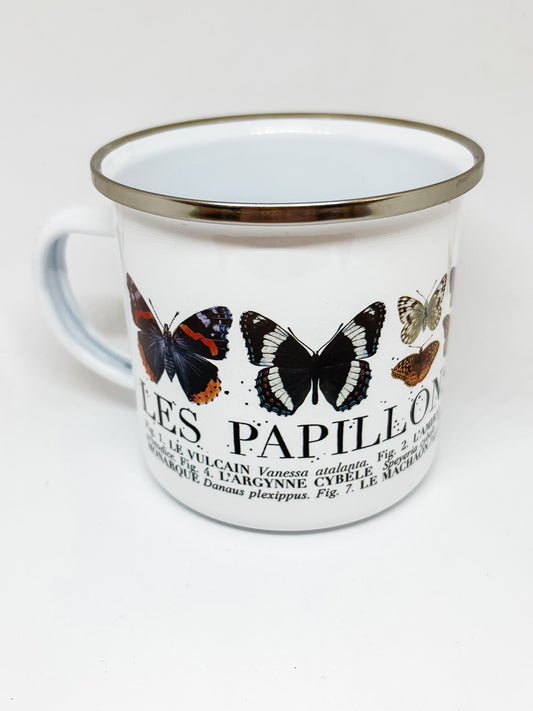 White enamel mug with silver rim and "Les Papillons" written with illustrations of butterflies
