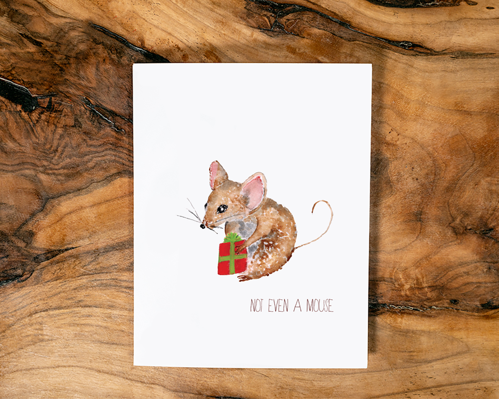 Card with a watercolour design of a mouse holding a red and green gift, with the caption "Not even a mouse", on a wooden surface