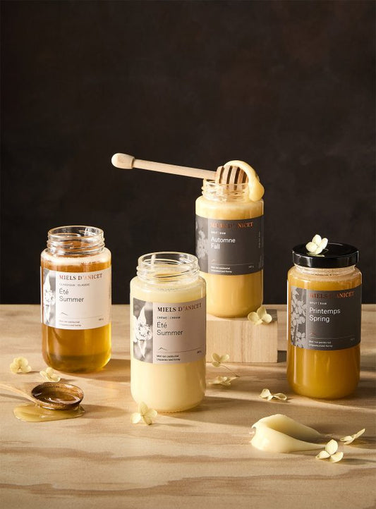 Jars of Miels D'Anicet honeys on a wooden surface