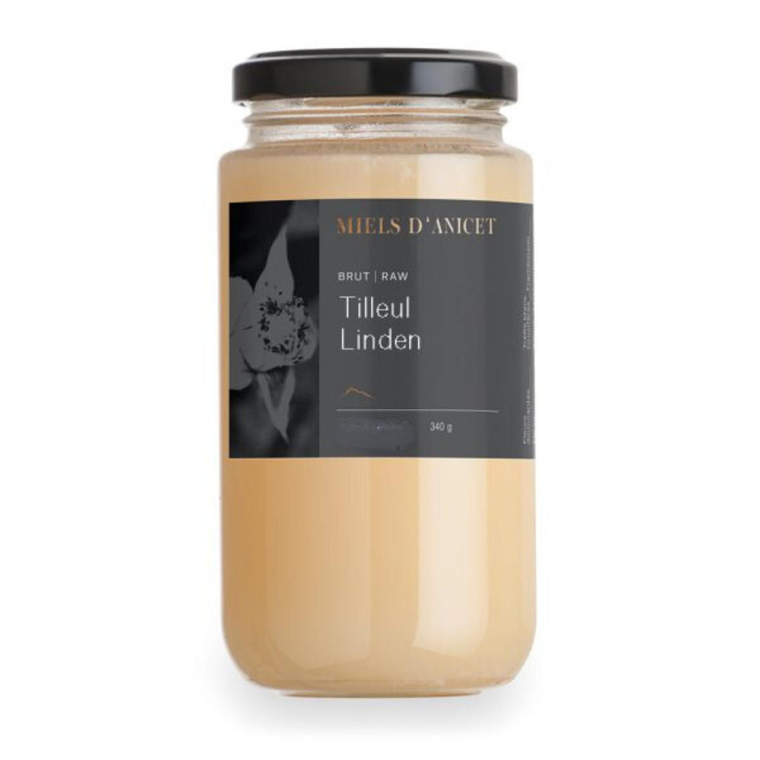 A glass jar of pale, creamy-colored raw honey labeled “Miels d’Anicet – Tilleul Linden,” with a black lid and a minimalist gray label, weighing 340 g