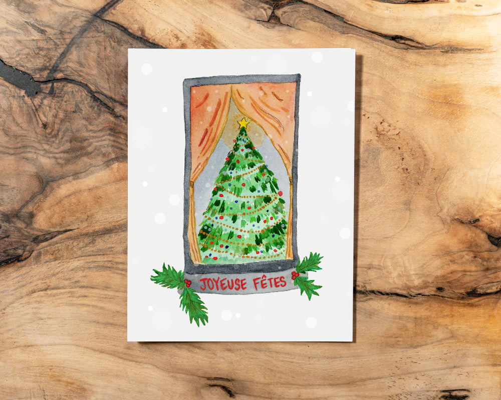 Christmas card with a decorated tree and 'Joyeuse Fétes' text on a wooden surface