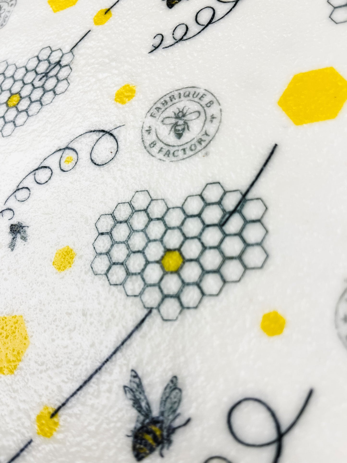 Close up of reusable beeswax wrap with honeycombs, bees, and B Factory logo