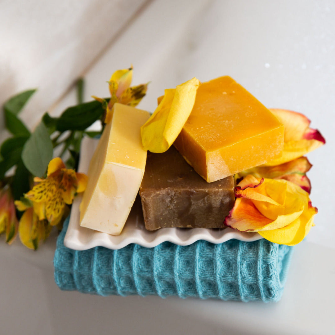 Handmade soap bars with flower petals piled on top of blue towel