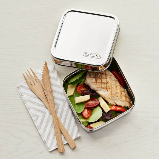 Chicken breast and salad in square stainless steel sandwich box with lid and wood utensils