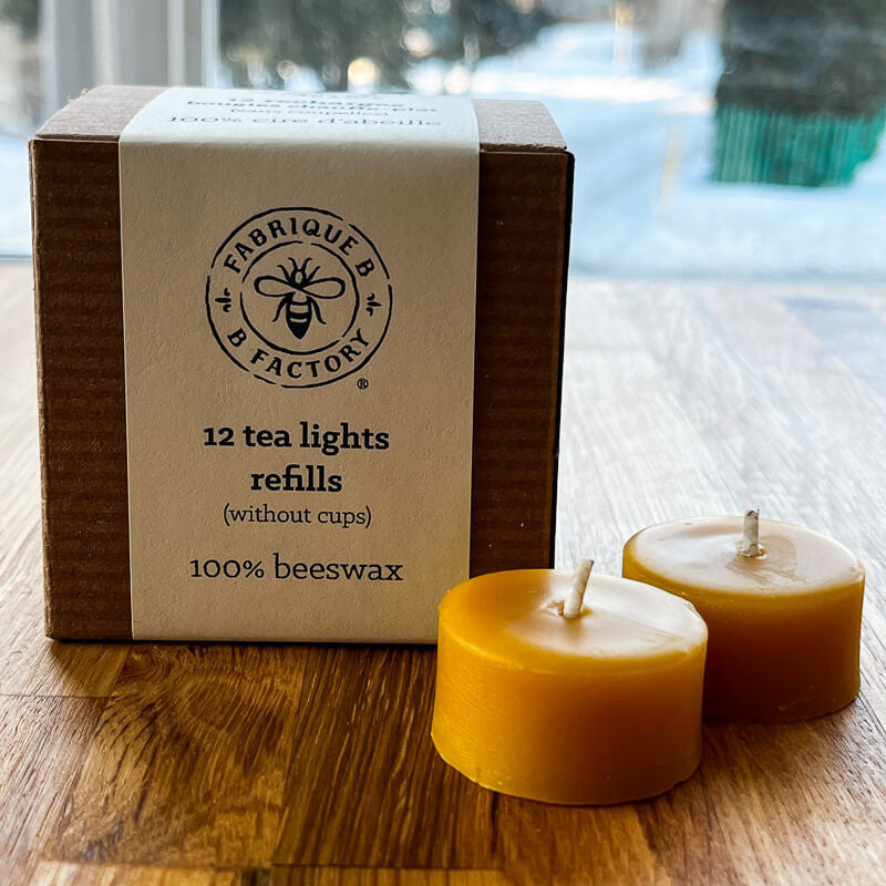 2 pure beeswax tea light candles next to carboard gift box that says B Factory 12 tea lights refills