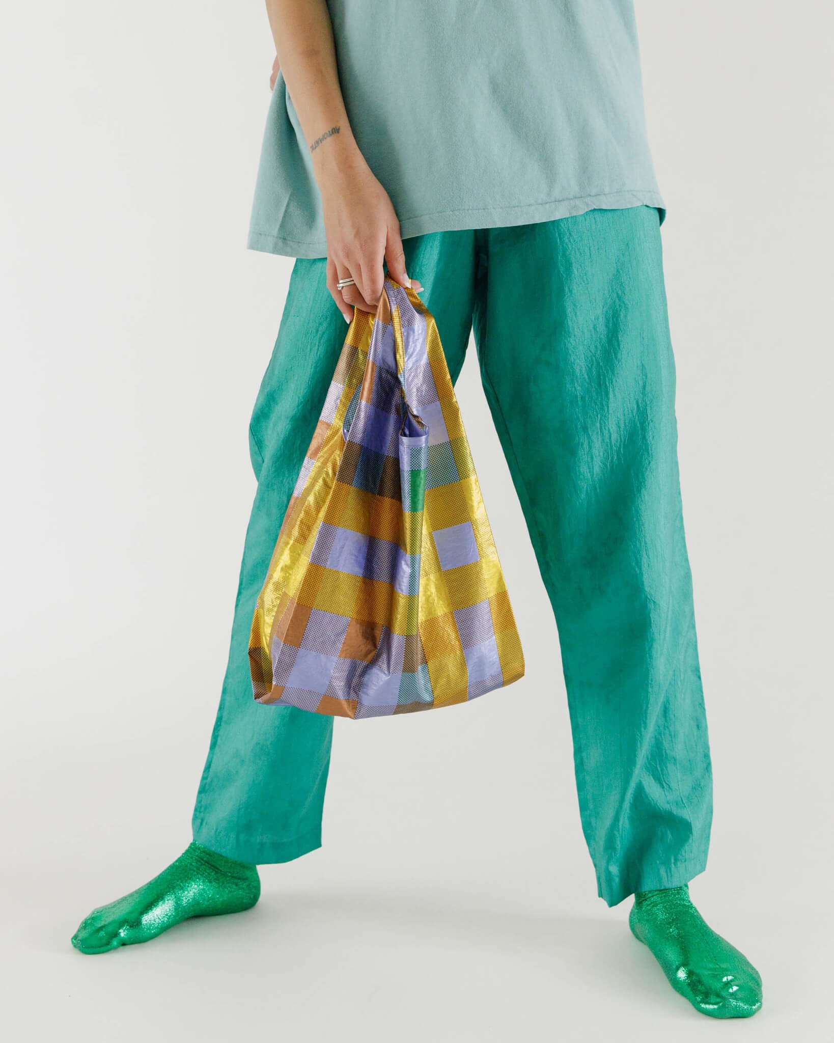 Person holding reusable shopping bag with metallic plaid pattern